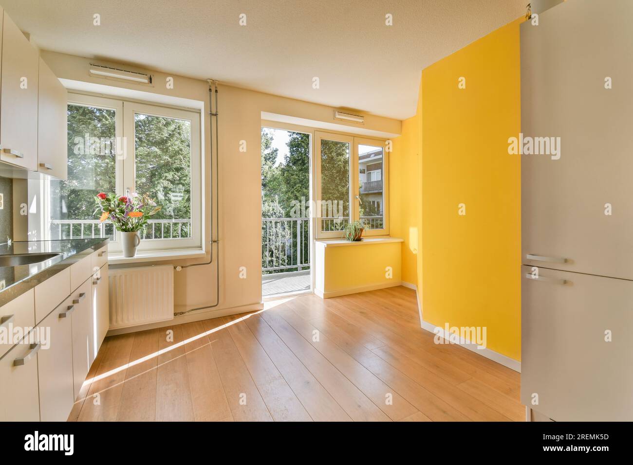 Eine Küche mit gelben Wänden und Holzfußboden in der Mitte des Zimmers, es gibt eine offene Tür, die zu einem führt Stockfoto