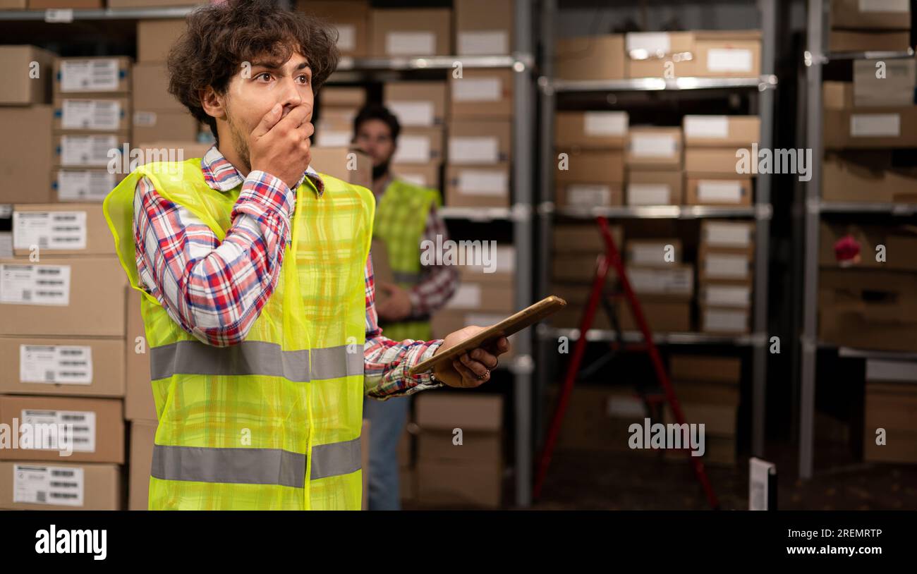 Schockierter arabischer Lagerarbeiter mit einem Tablet in der Hand Probleme beim Laden Stockfoto