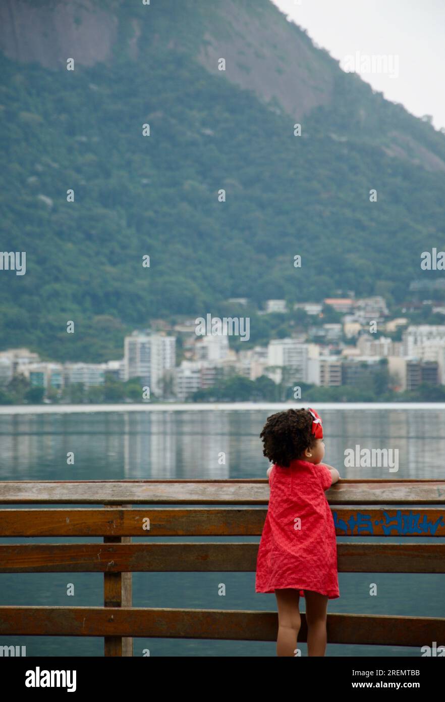 Ein kleines Mädchen, das auf einen See schaut Stockfoto