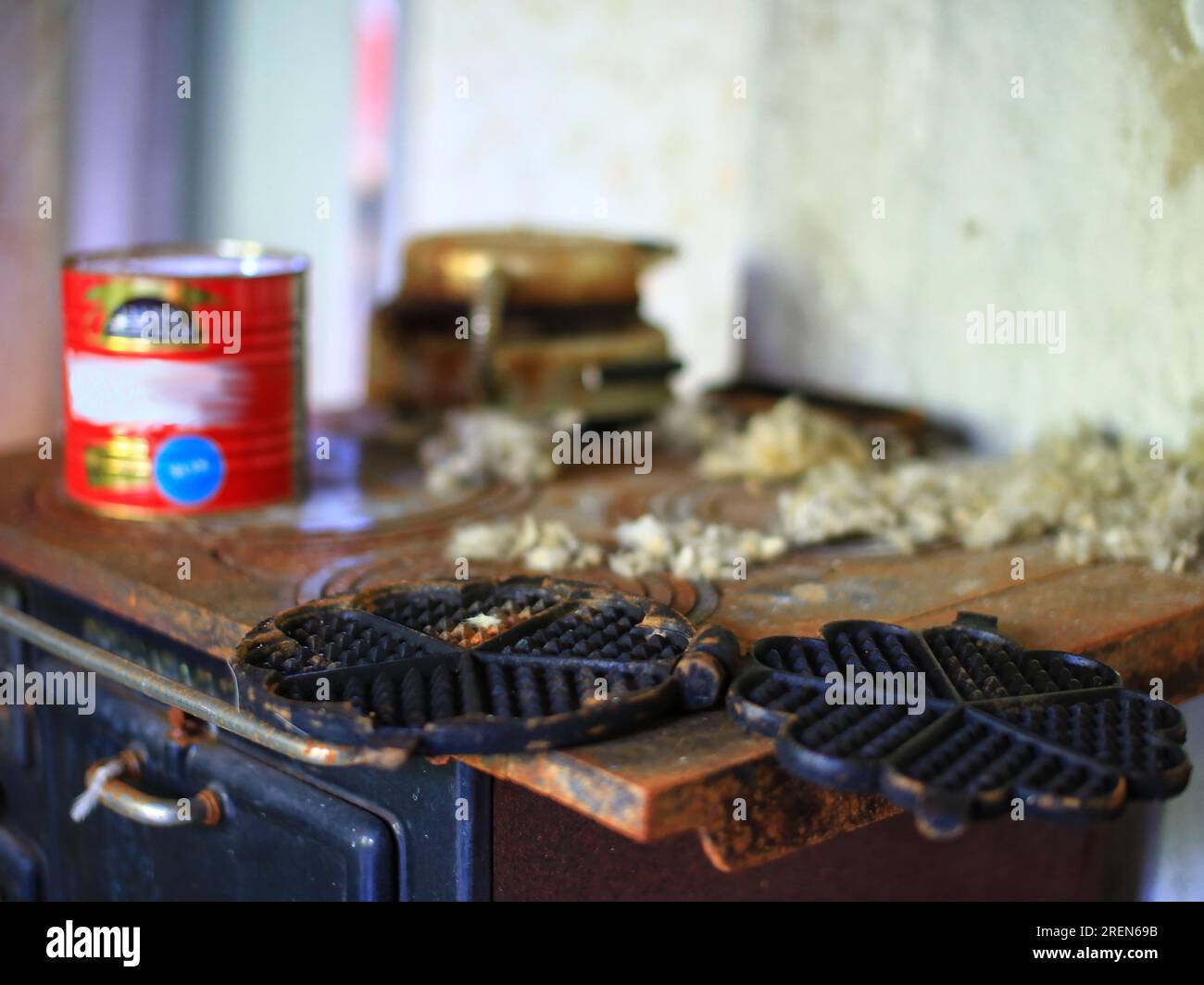 Waffeleisen auf einem rostigen Ofen in einem verlassenen Haus. Stockfoto