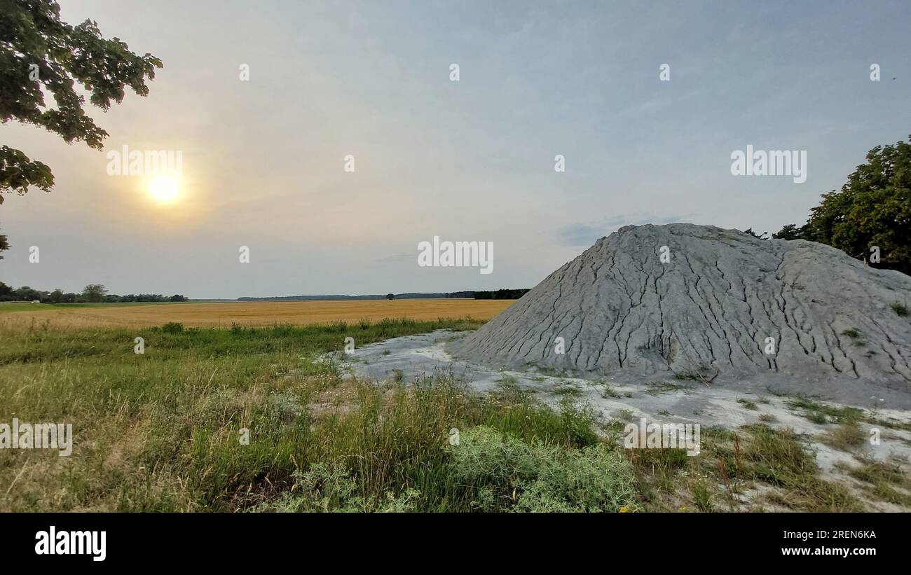 Landwirtschaftliche Landschaft mit grauem Zement- oder Kies, die wie ein Vulkan aussieht. Stockfoto