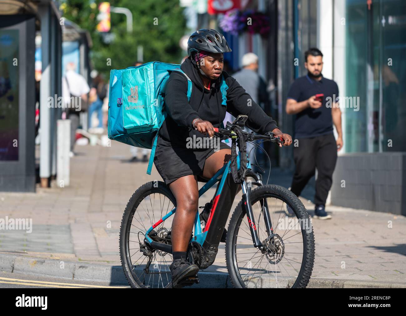 Radfahrer in einer Stadt fährt Fahrrad mit Deliveroo Food, online bestellt, UK. Stockfoto