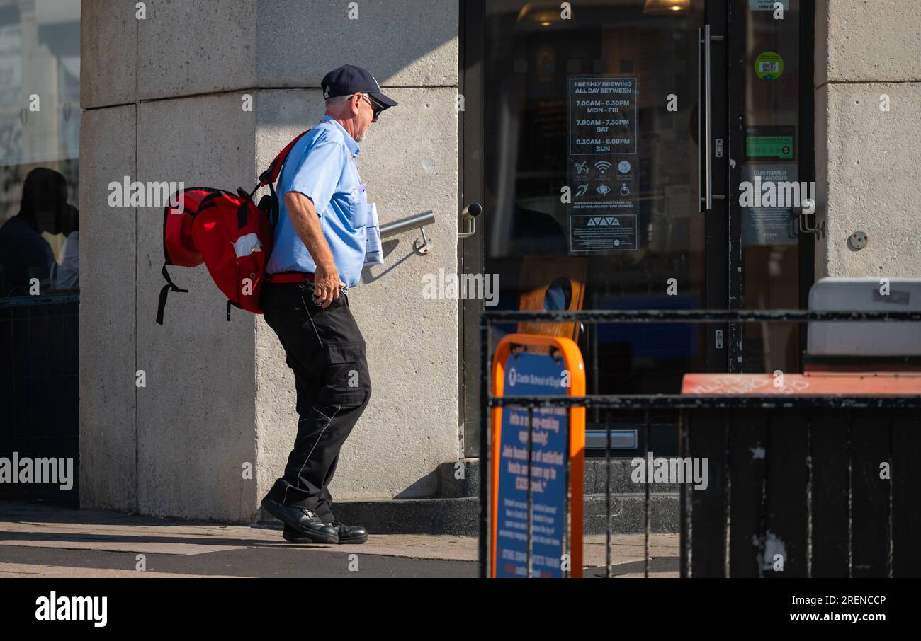 Royal Mail Postman oder Postbote, die Briefe und Post an Geschäftsräume im Stadtgebiet von England, Großbritannien, liefern. Beruf. Stockfoto