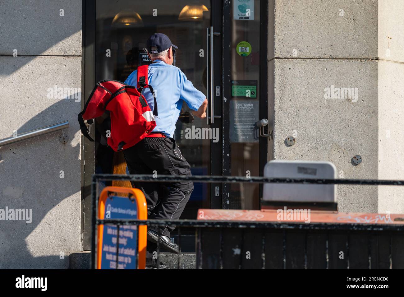 Royal Mail Postman oder Postbote, die Briefe und Post an Geschäftsräume im Stadtgebiet von England, Großbritannien, liefern. Beruf. Stockfoto