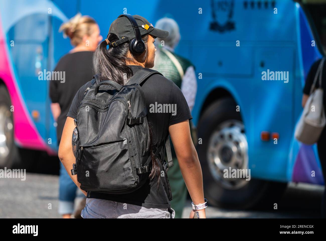 Junge Frau, die geschäftig in der Stadt unterwegs ist und über-Ohr-Kopfhörer trägt. Stockfoto