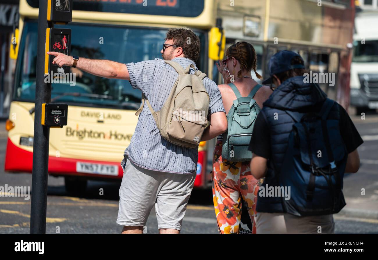Ein Pärchen in einer geschäftigen Stadt, das scheinbar verloren war und an einem Sommertag in England, Großbritannien, eine Wegbeschreibung gab. Möglicherweise Touristen oder Besucher. Fußgänger. Stockfoto