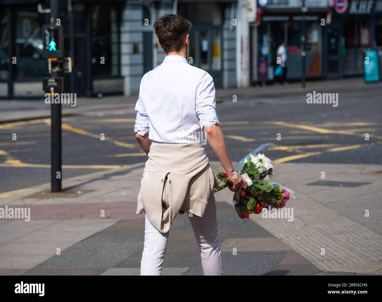 Junger Mann, der läuft, Stadt, Sommer, trägt, ein paar Blumen, England, Großbritannien. Liebeskonzept, romantisches Konzept, Romantik, junge Liebe. Blumenstrauß. Stockfoto