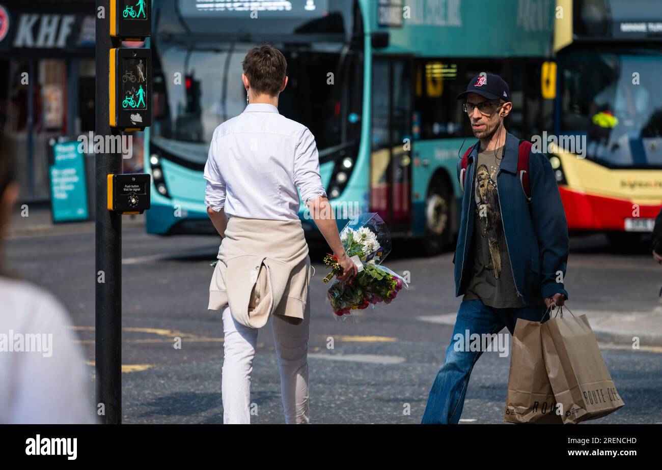 Ein junger Mann, der im Sommer in einer Stadt spaziert, mit einem Blumenstrauß in Großbritannien. Liebeskonzept, romantisches Konzept, Romantik, junge Liebe. Blumenstrauß. Stockfoto