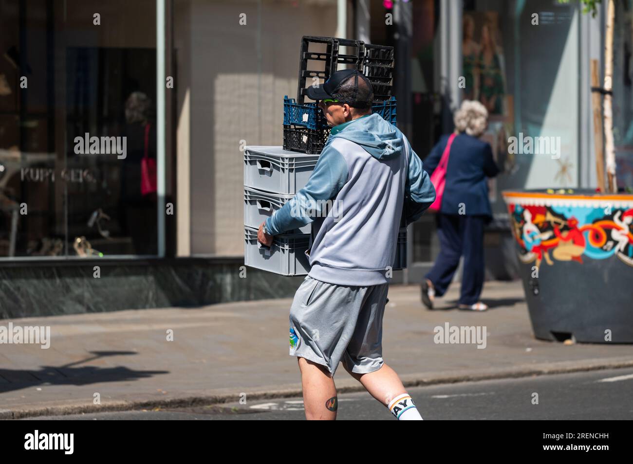 Mann mit schweren Kisten als Teil einer Geschäftslieferung in einer Stadt in England, Großbritannien. Stockfoto