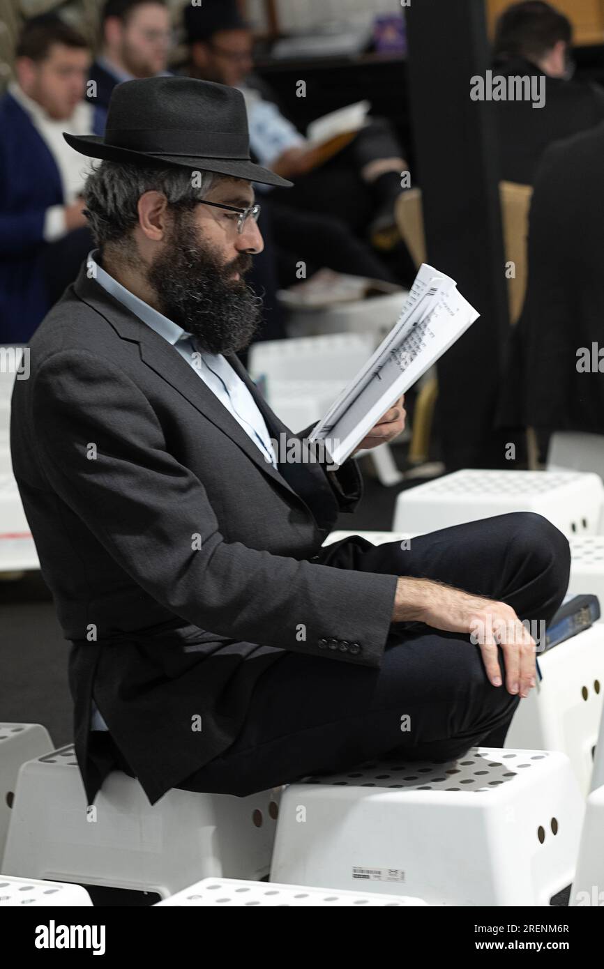 Bei der Morgenfeier von Tish B'Av sitzen orthodoxe jüdische Männer auf niedrigen Hockern, die den Trauergesetzen des Tages entsprechen. In Rockland County, NY Stockfoto