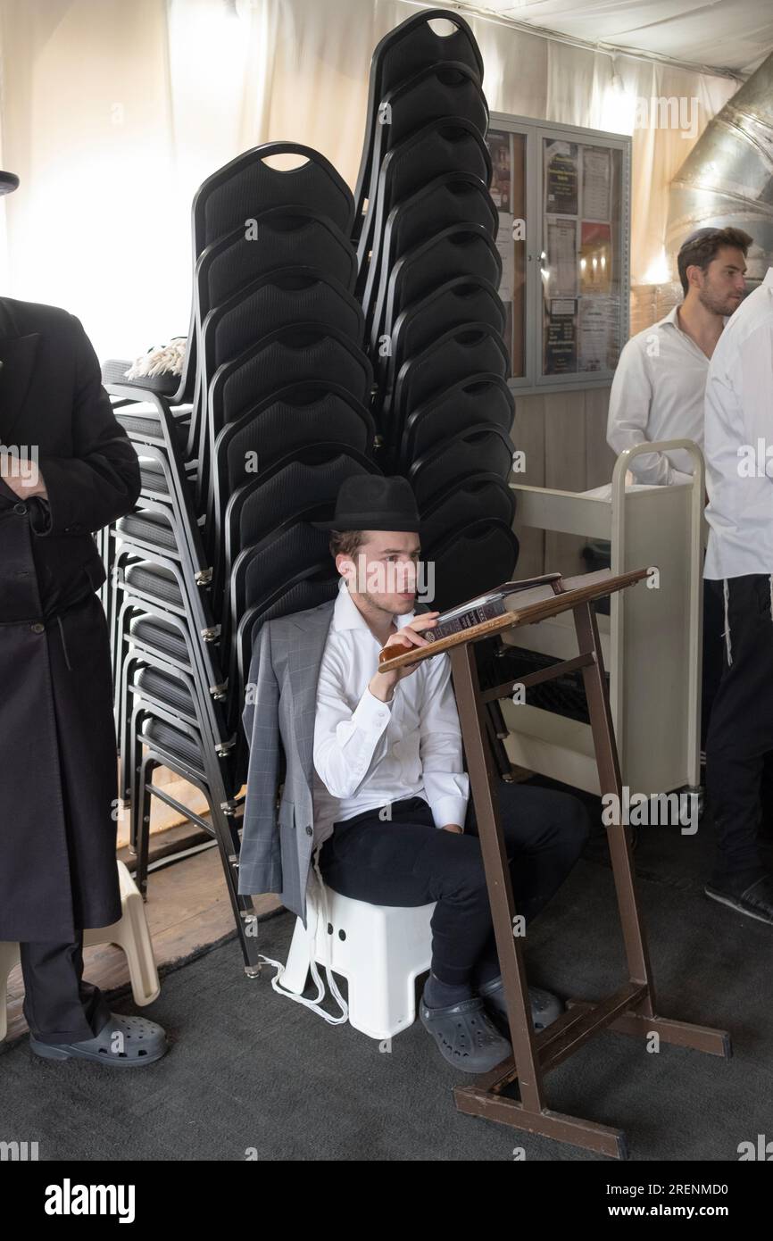 Bei Tisha B'AV Services beobachtet ein junger Mann die trauernden Aspekte des Tages, indem er fastet, auf einem niedrigen Sitz sitzt und keine Lederschuhe trägt. In Rockland. Stockfoto