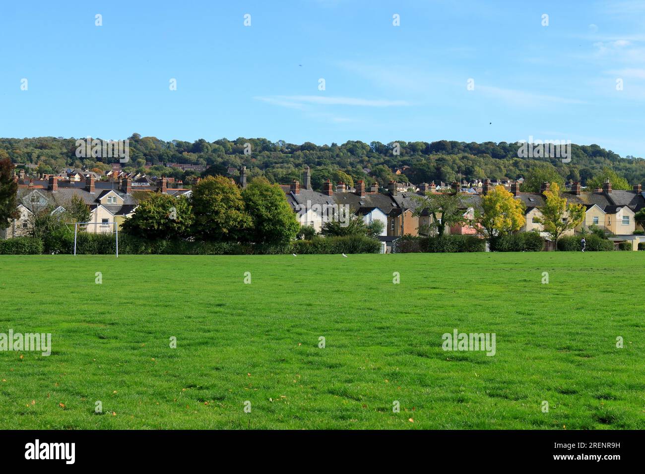 Englische Landschaft. Ein grünes Feld, ferne Gebäude und Bäume mit blauem Himmel darüber. Stockfoto