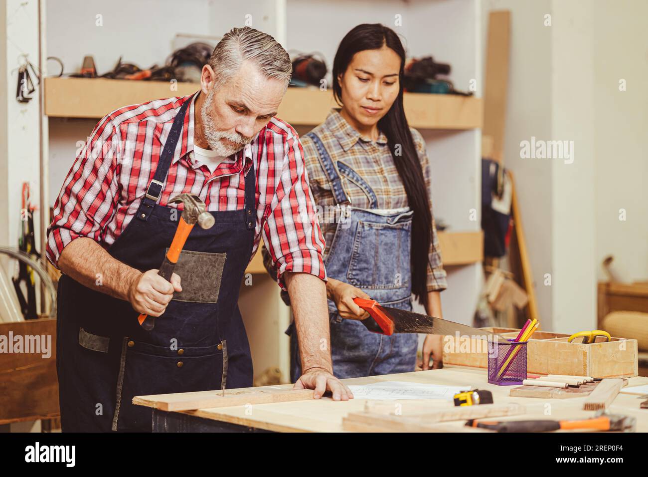 Cheffachmann, weiß, männlicher heimwerker, Holzarbeiten, reparieren Heimmöbel in der Werkstatt, Ehefrau hilft. Stockfoto