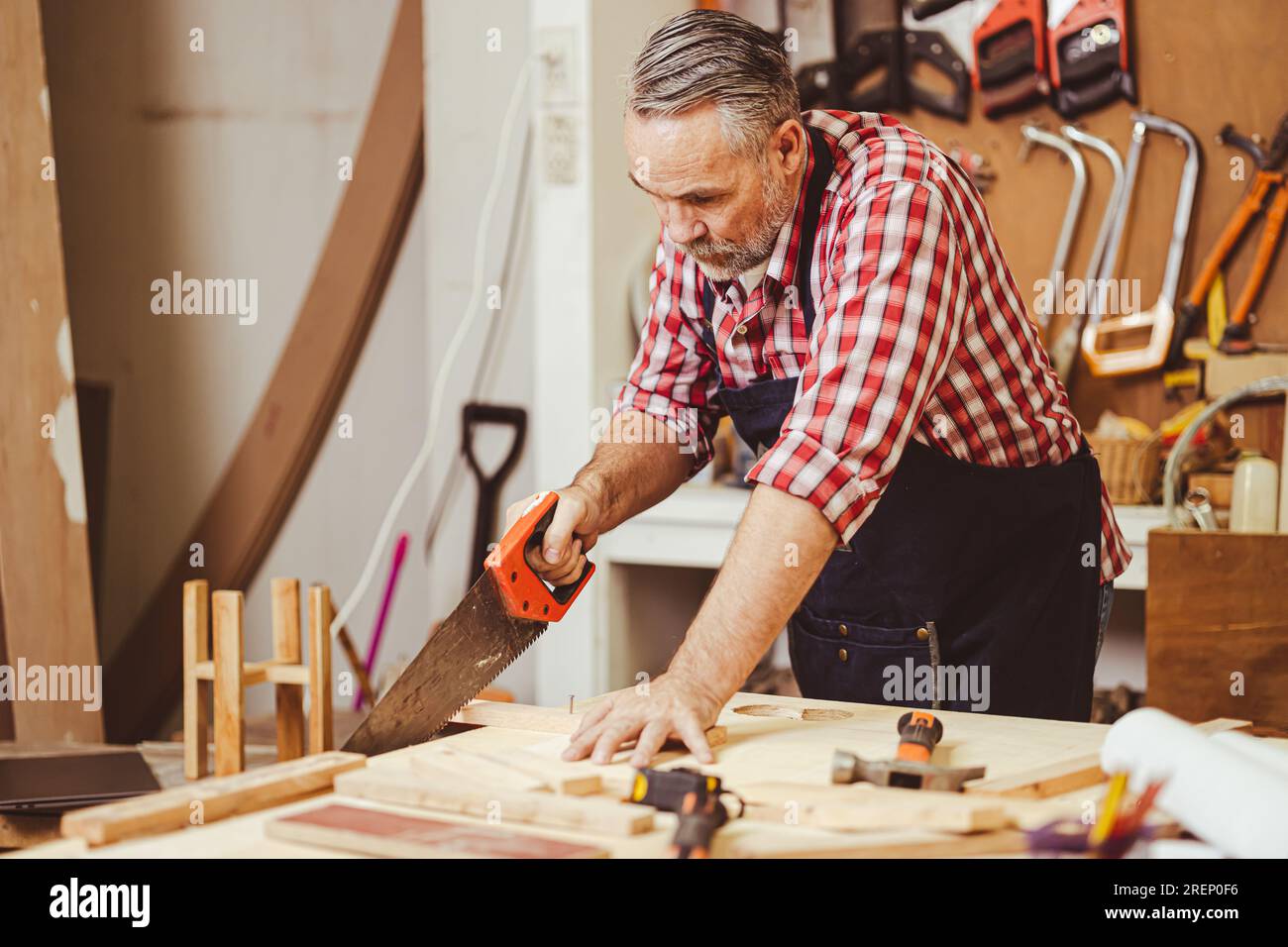 Leitender professioneller männlicher Kaukasier-heimwerker-Säge Holz schneiden und Heimmöbel in der Holzwerkstatt herstellen, Hausrenovierung. Stockfoto
