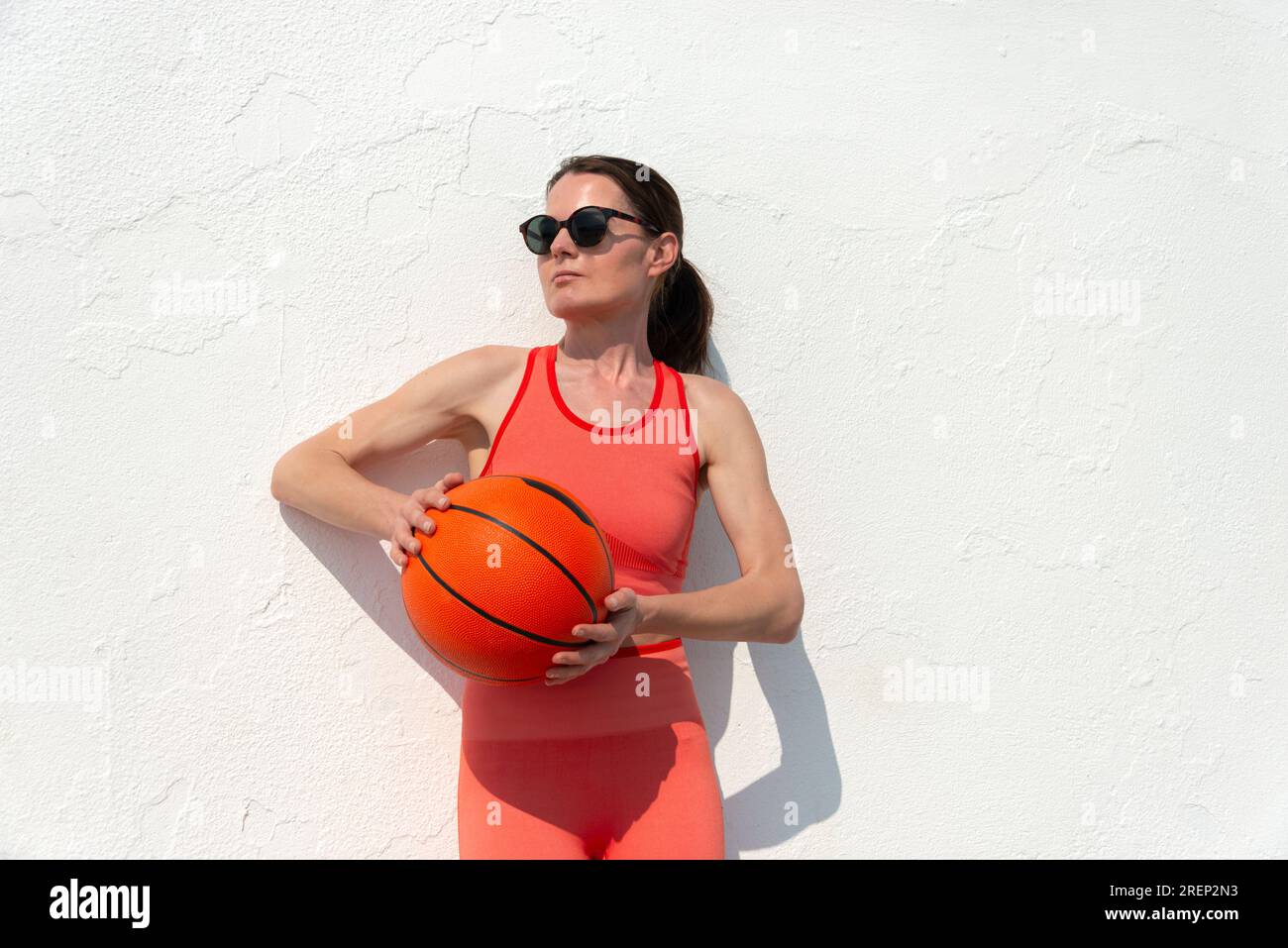Basketballspielerin, hält einen Basketball, draußen in der Sonne. Stockfoto