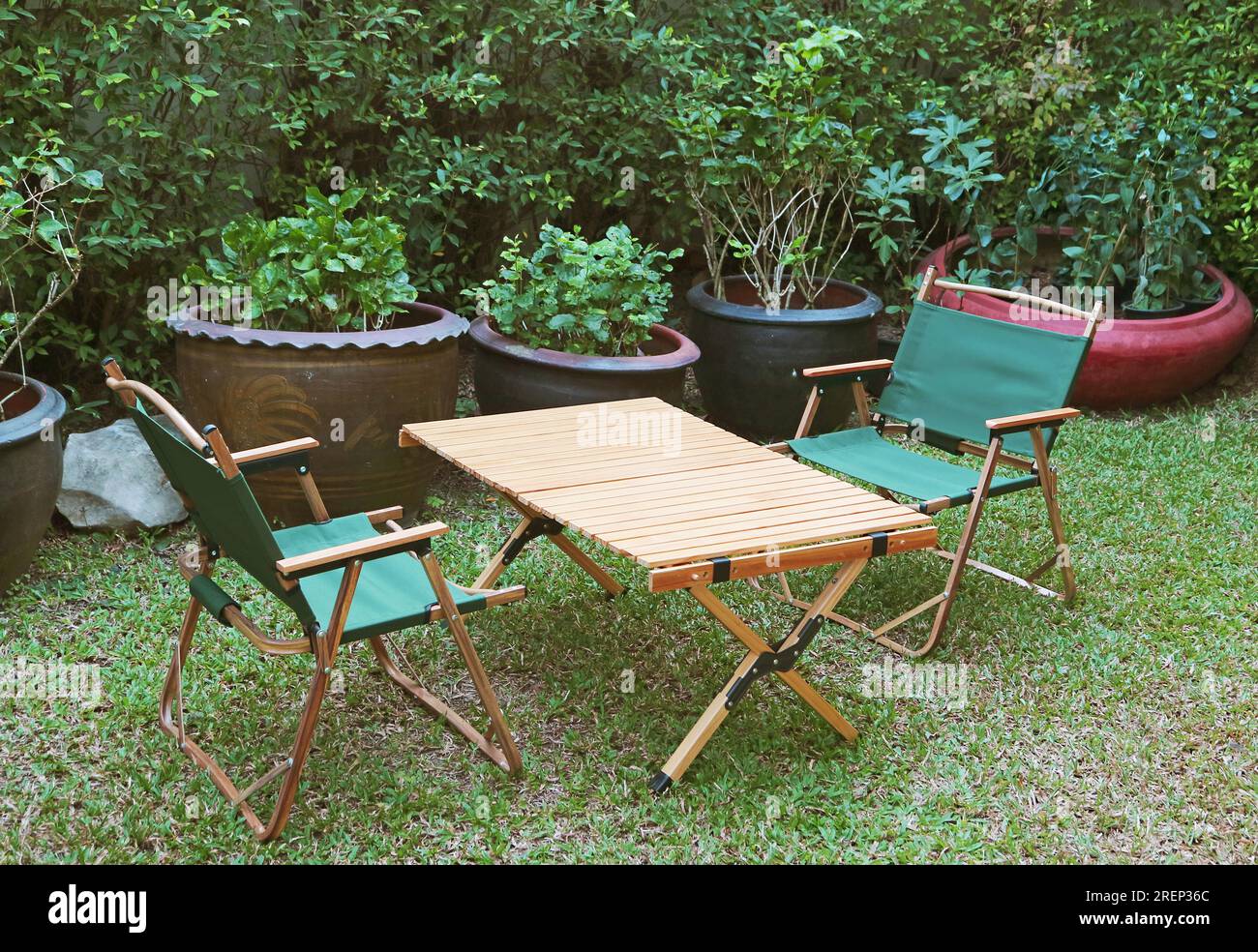 Ein Paar tragbare Klappstühle und ein Holztisch im Garten Stockfoto