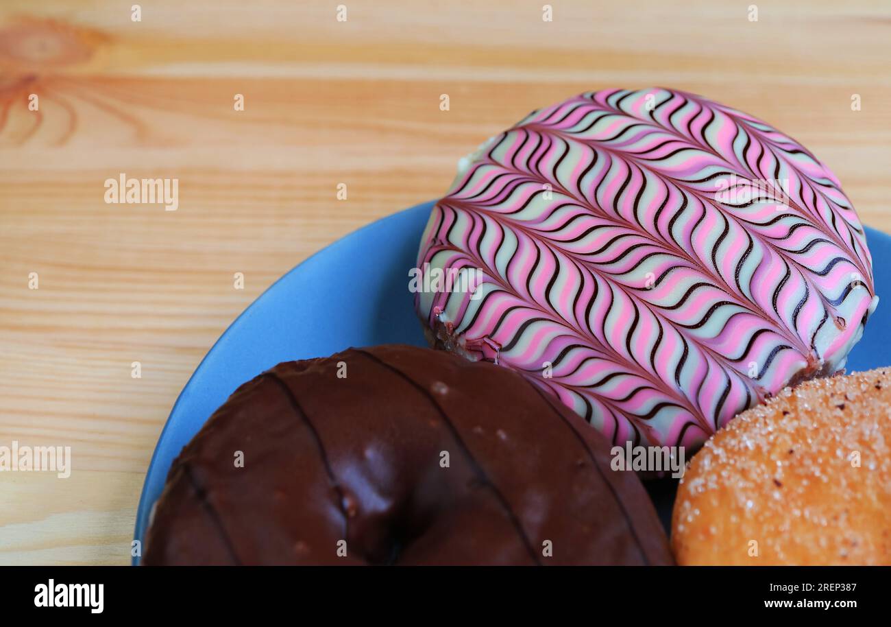 Teller mit verschiedenen Donuts mit selektivem Fokus, serviert auf einem Holztisch Stockfoto