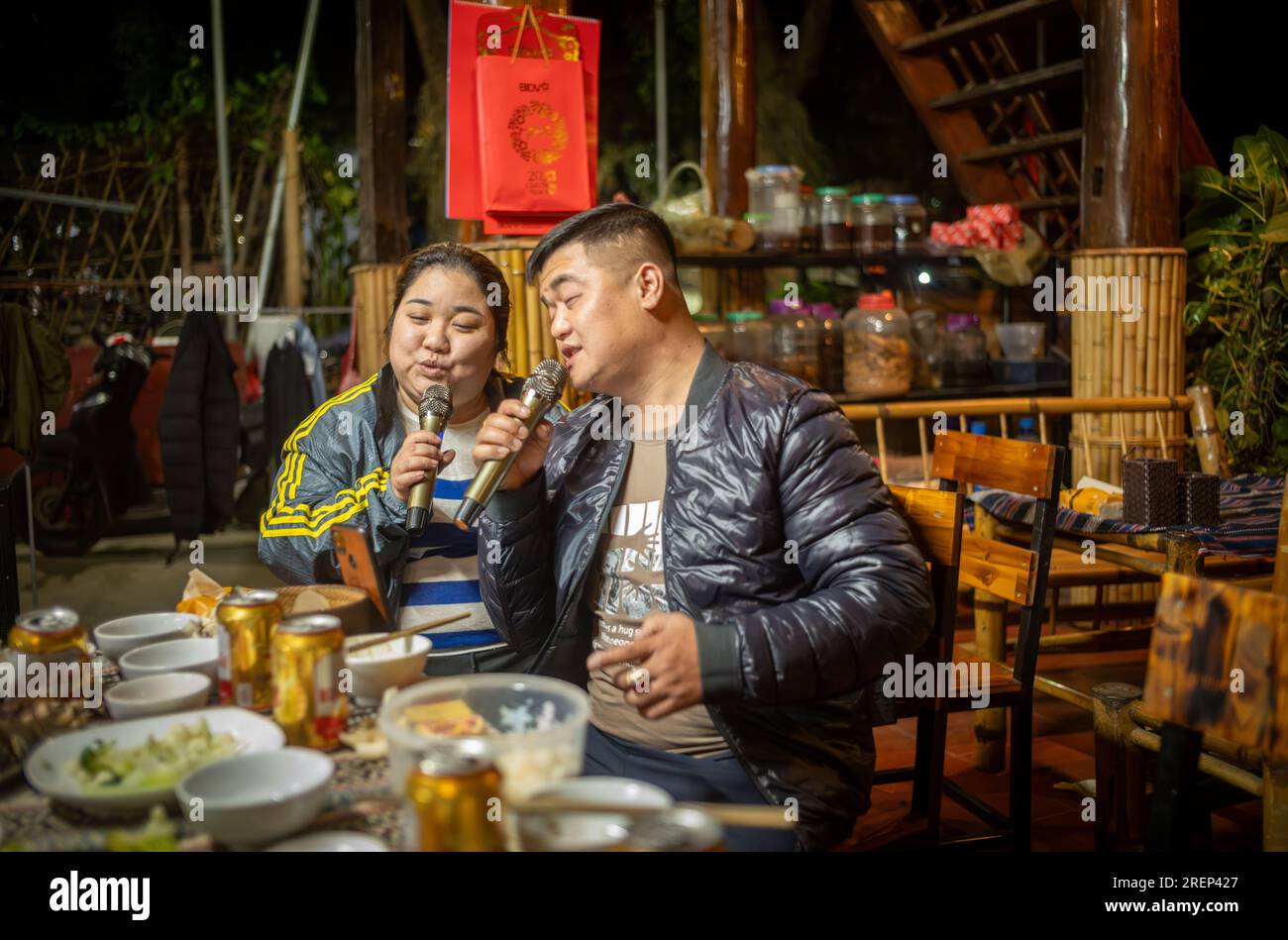 Ein weißes thailändisches ethnisches Minderheitenpaar singt nach dem Abendessen in seiner Gastfamilie in Mai Chau, Vietnam, zusammen Karokellieder. Stockfoto