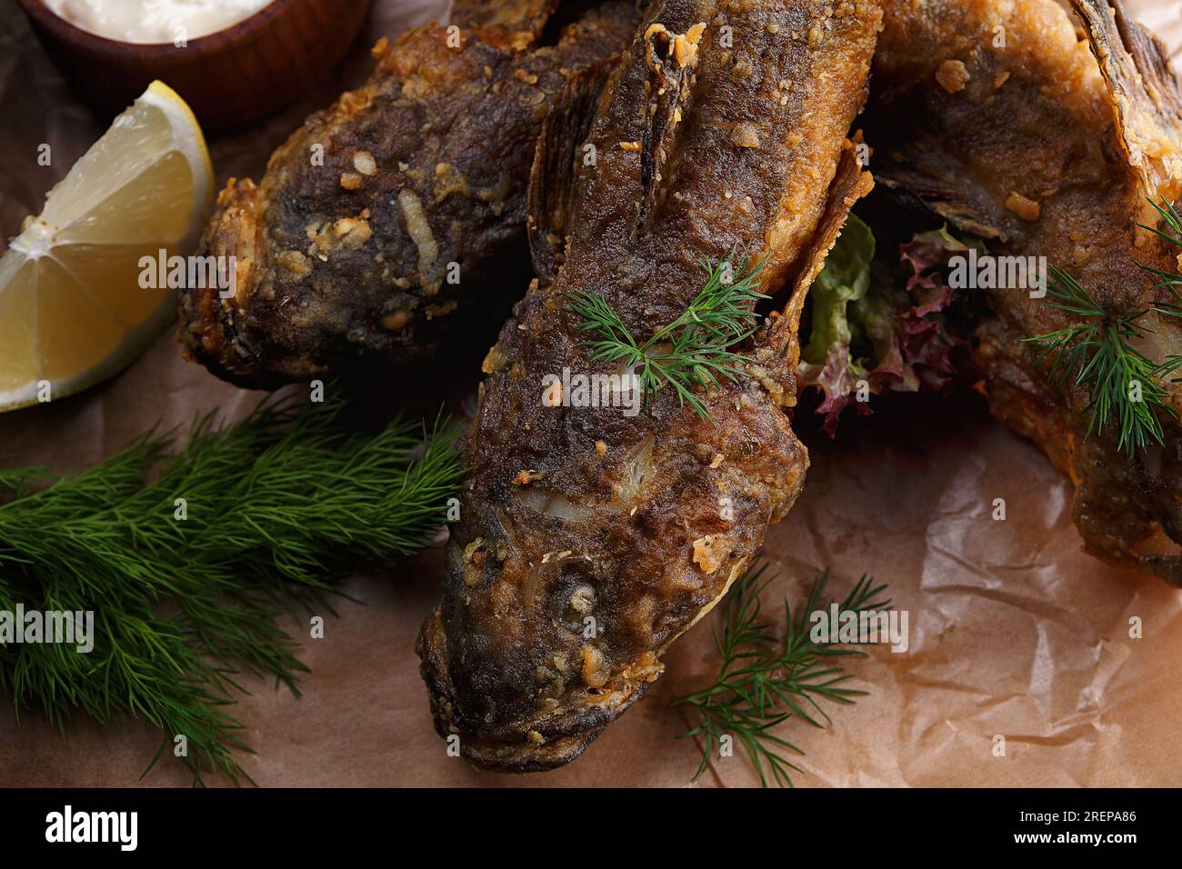 Gebratene Fischziege (Gobiiidae) mit Sauce auf einem Holzbrett Stockfoto