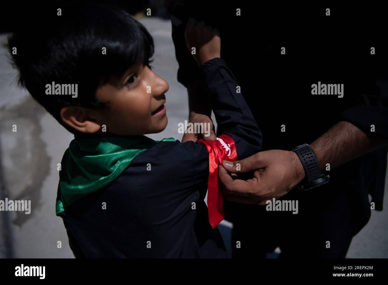 A Shiite Muslim ties a band to a child during a procession to mark ...