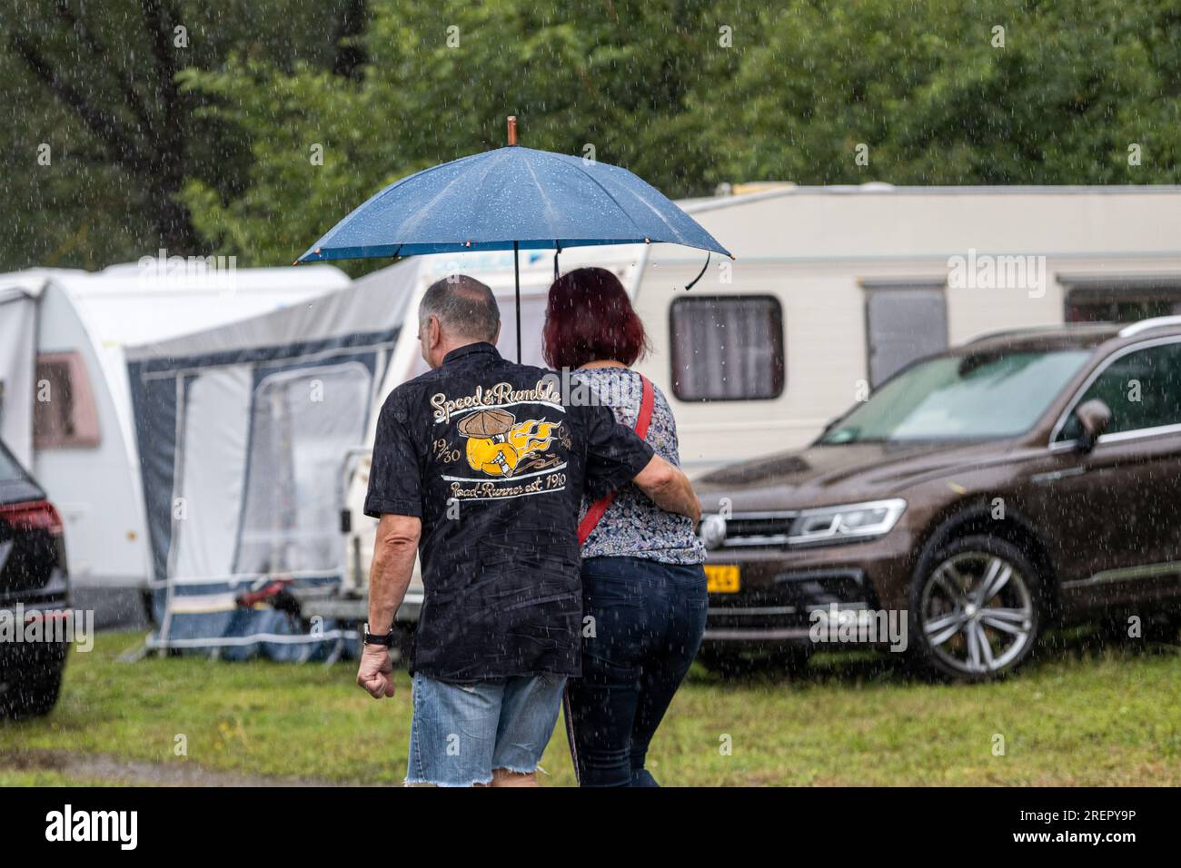 29. Juli 2023, Hessen, Wettenberg-Wißmar: Besucher des Golden Oldies Festivals mit Sonnenschirmen zu ihren Karawanen auf dem Wißmarer See Campingplatz. Trotz des schlechten Wetters sind viele Campingplätze in Hessen voll belegt. Foto: Christian Lademann/dpa Stockfoto