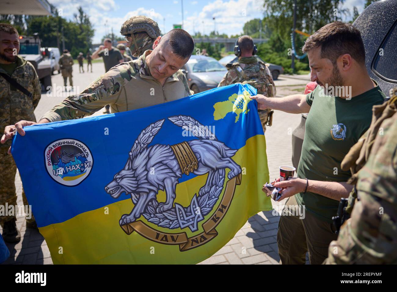 Donezk, Ukraine. 29. Juli 2023. Der ukrainische Präsident Wolodymyr Zelenskyy, richtig, lächelt, während ein Soldat ihn bittet, während eines Besuchs an Frontpositionen in der Region Donezk am 29. Juli 2023 im Oblast Donezk, Ukraine, eine Einheitenflagge zu unterzeichnen. Zelenskyy besuchte SOF-Kommandos anlässlich des Tages der Special Operations Forces und hielt an einer Tankstelle auf dem Weg an, um Anhänger zu begrüßen. Kredit: Pool Photo/Pressestelle Des Ukrainischen Präsidenten/Alamy Live News Stockfoto