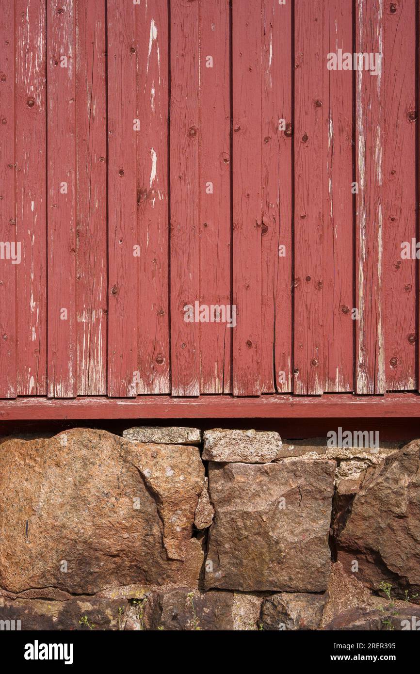 Rote Holzmauer und Steinfundament eines alten Hauses in Loviisa, Finnland. Stockfoto
