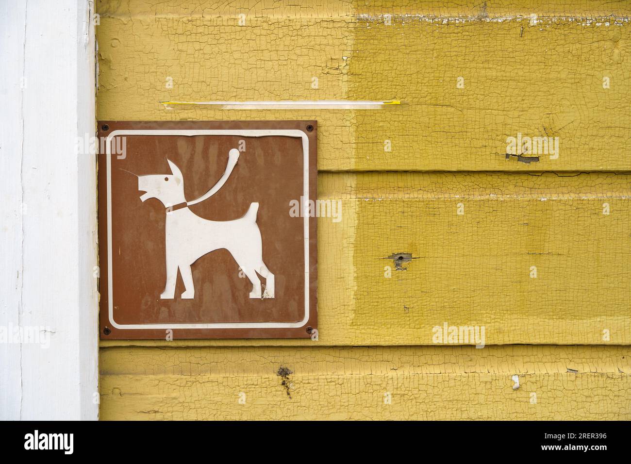 Braunes Hundeparkplatz-Schild an der Wand eines alten gelben Holzgebäudes. Schließen. Stockfoto