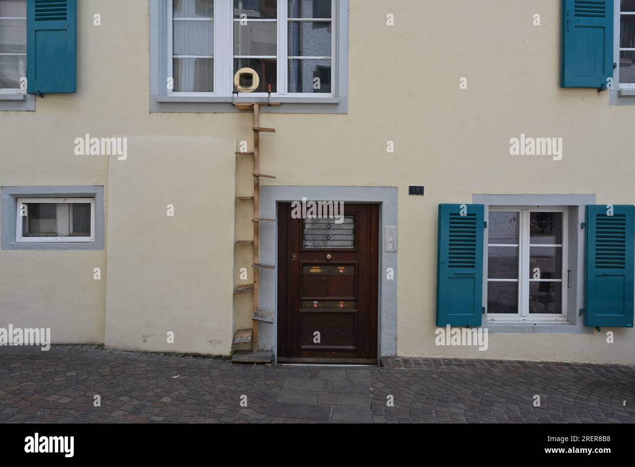 Ein Haus mit einem Fenster mit Eingang für eine Katze und einer hölzernen vertikalen Leiter. Stockfoto