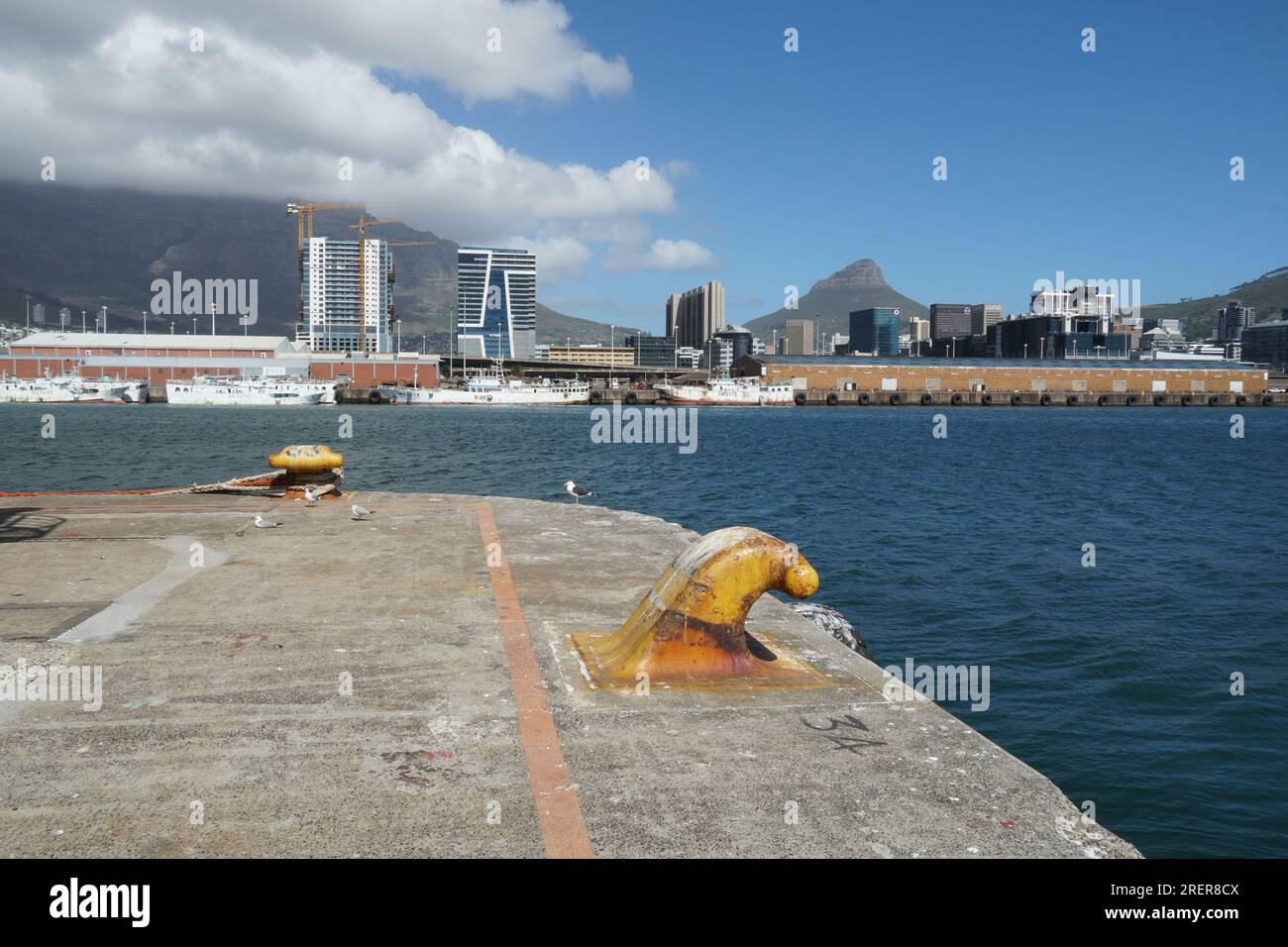 Stadtbild von Kapstadt mit hochmodernen Gebäuden, Blick vom Pier mit gelben Pollern. Stockfoto