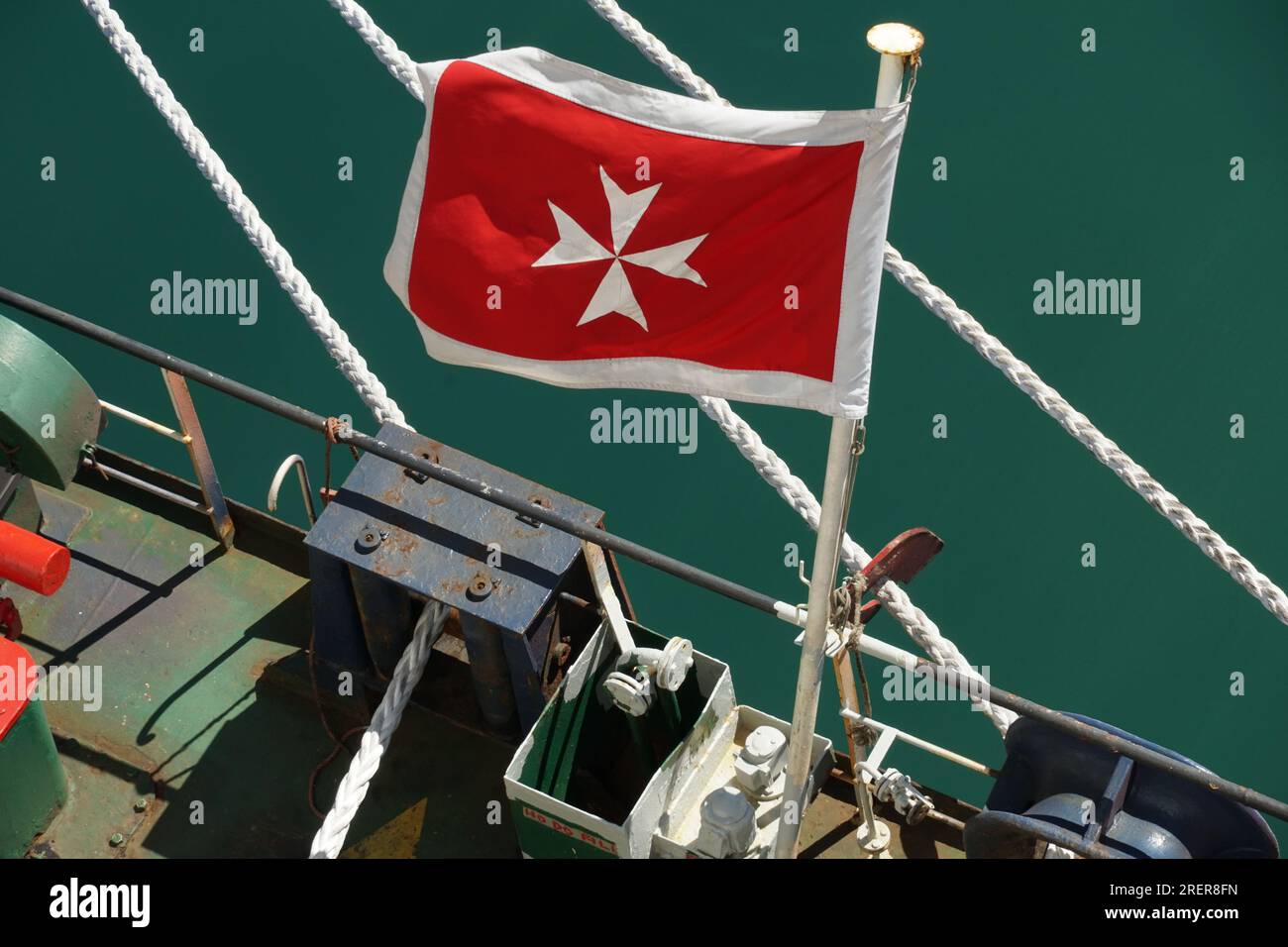 Maltesische Flagge, rote Fahne mit weißem Kreuz, die im hinteren Teil des Handelsschiffes fliegt. Stockfoto