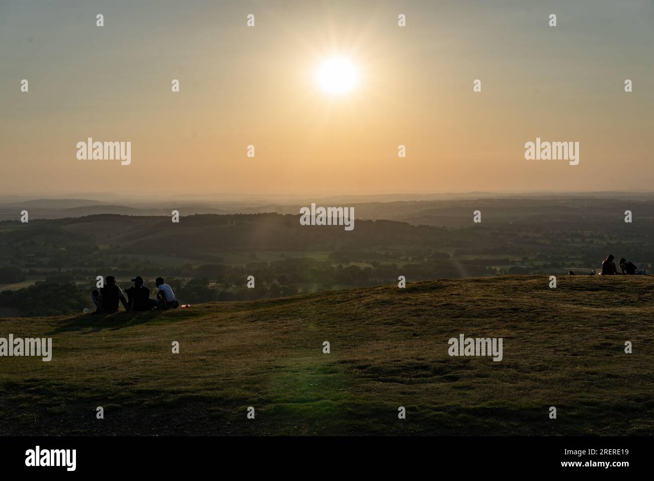 Eine Gruppe von Menschen, die die Schönheit der Natur bei Sonnenaufgang bewundern und beobachten, wie die Sonne über einem entfernten Horizont über einen malerischen Hügel aufgeht. Blick von Briti Stockfoto