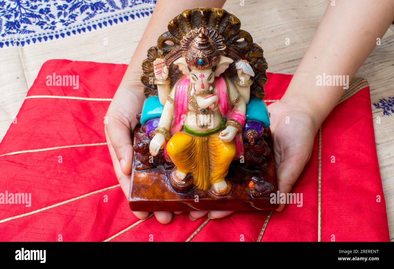 Sie halten ein wunderschönes Idol oder eine Statue Gottes Ganesh in der Hand mit rotem Hintergrund. Glückwunschkarte Ganesh Chaturthi mit Kopierfeld. Stockfoto