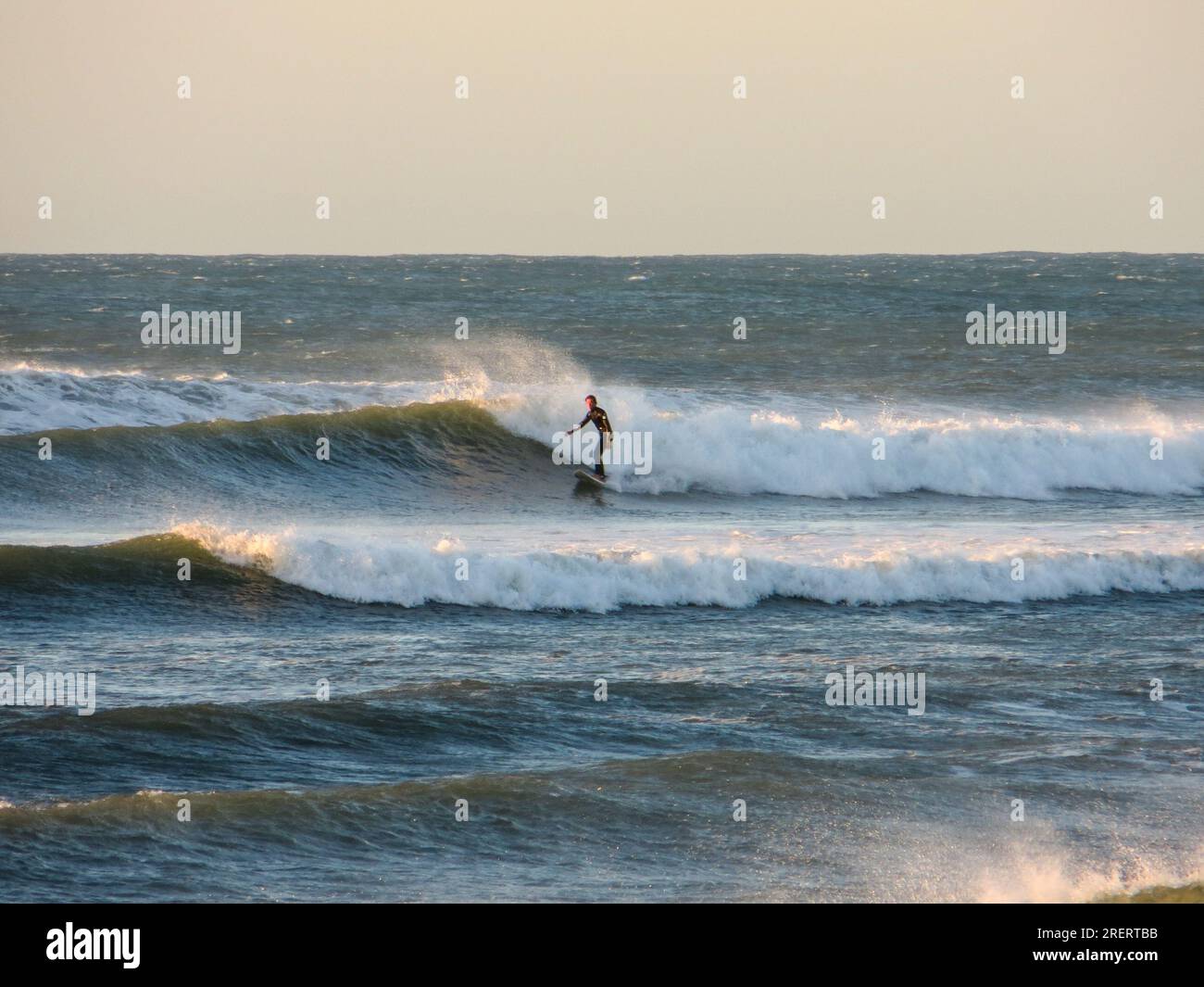 Einsamer Surfer, der vor der Küste von Taranaki auf Neuseelands Nordinsel Wellen bricht Stockfoto