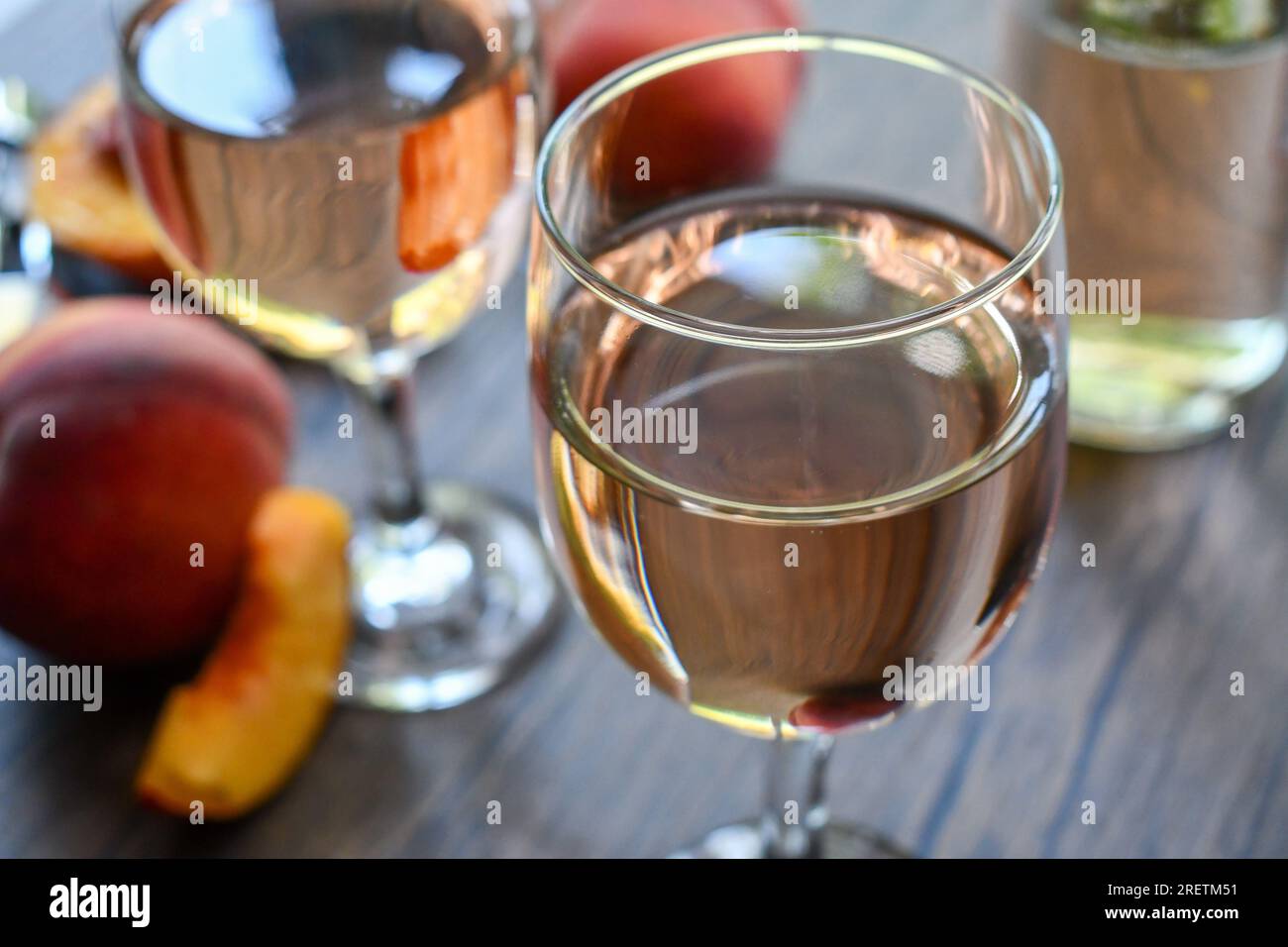Gläser Pfirsichwein auf einem dunklen Holztisch Stockfoto