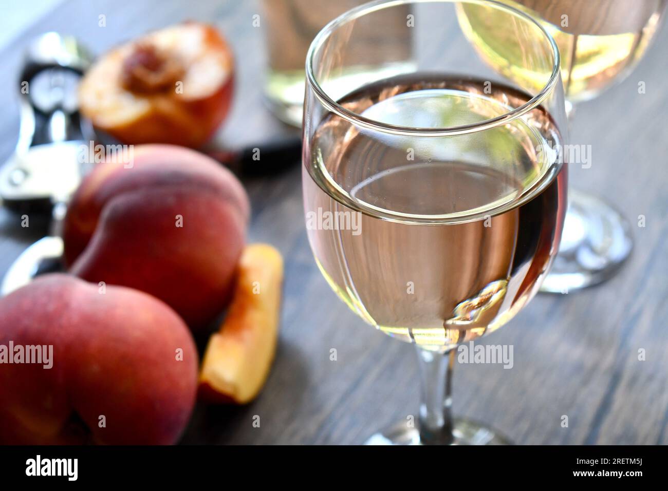 Gläser Pfirsichwein auf einem dunklen Holztisch Stockfoto