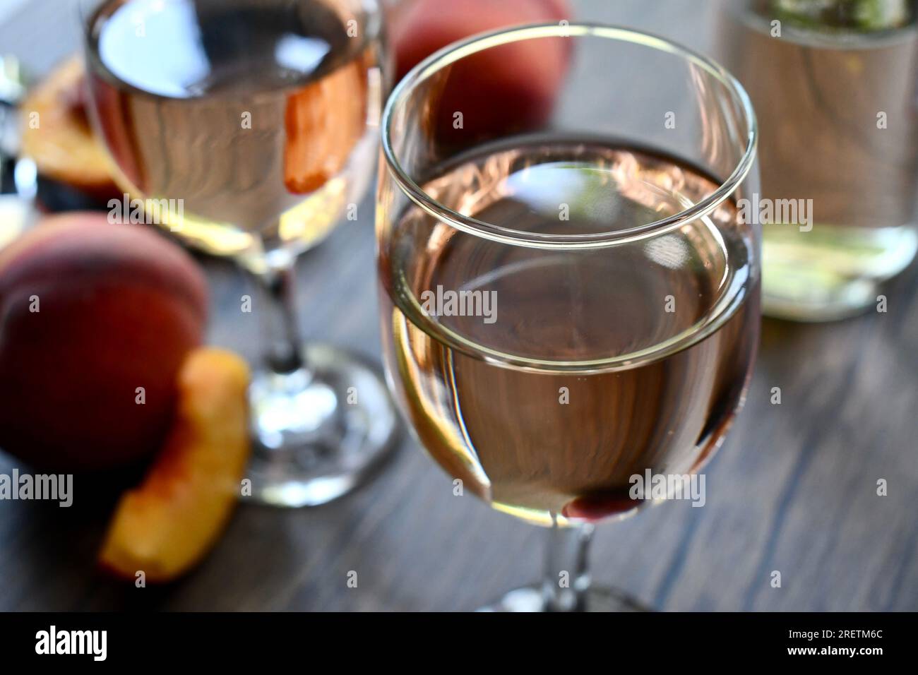 Gläser Pfirsichwein auf einem dunklen Holztisch Stockfoto
