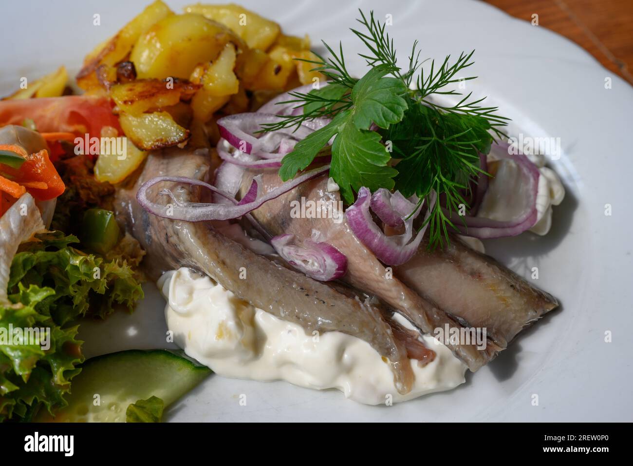 Matjes Fillet Hausfrauenart, Junges eingelegtes Hering Hausfrau Style mit Äpfeln und saurer Sahne, mit Roastkartoffeln und Salat Stockfoto