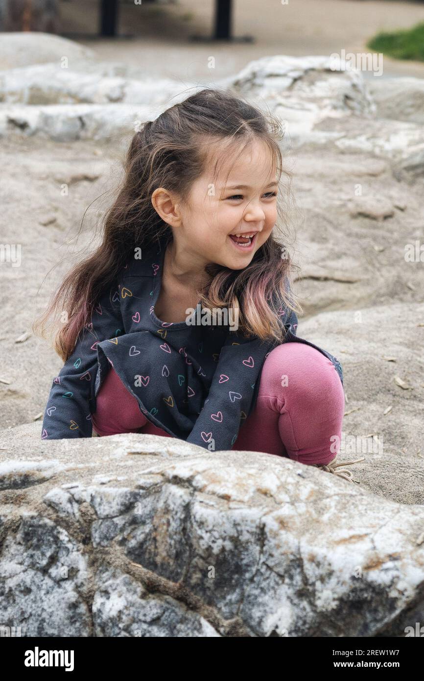 Ein brünettes Kind spielt auf einem Spielplatz Stockfoto