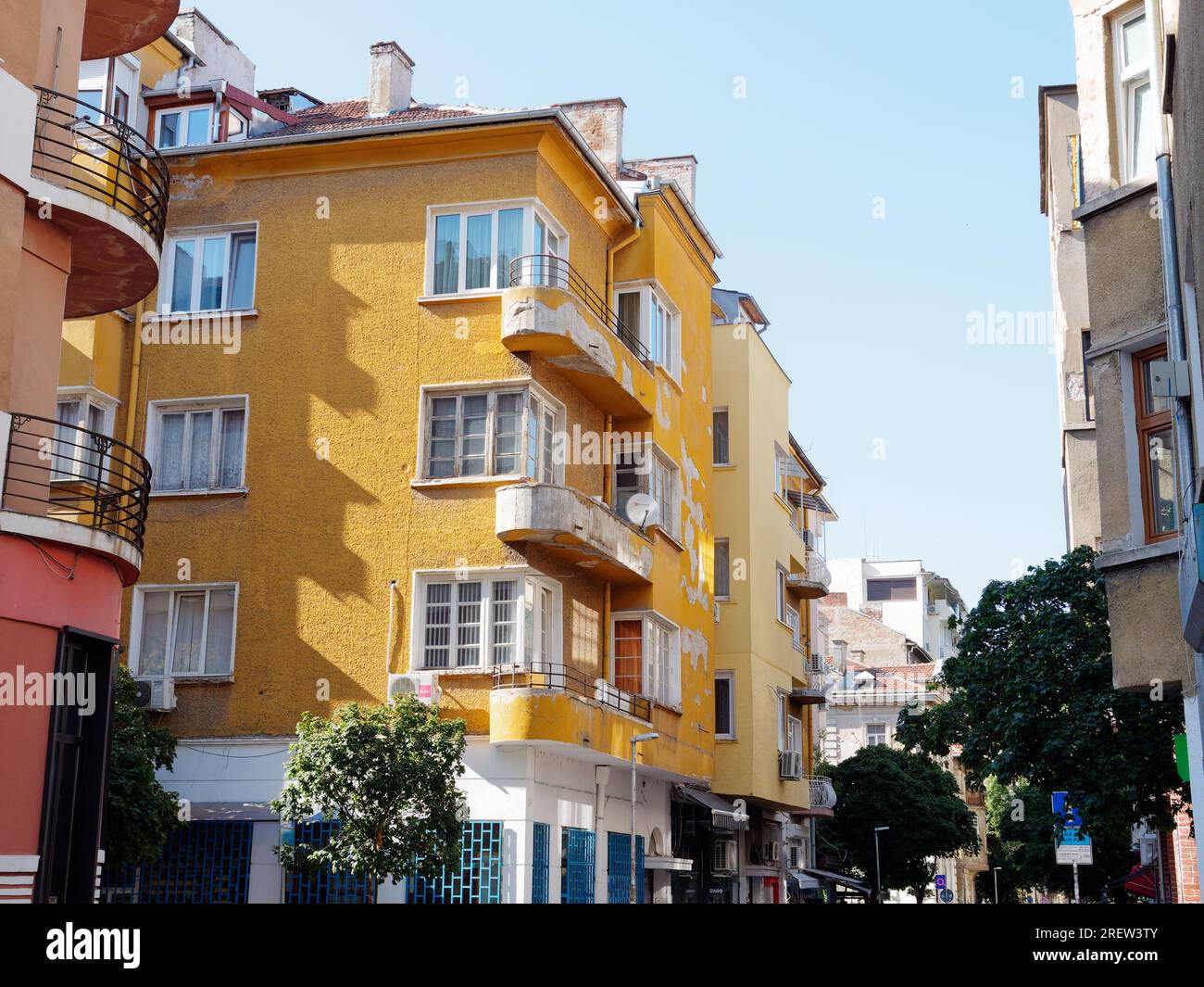 Schlecht gepflegtes gelbes Apartmentgebäude mit verfallender Farbe und zerbröckeltem Balkon. Sofia, Bulgarien. Juli 2023 Stockfoto