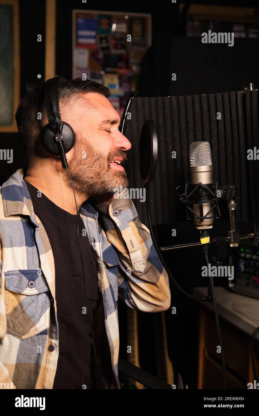 Sängerin mit Kopfhörern, die ein neues Album in einem Aufnahmestudio aufnimmt. Stockfoto