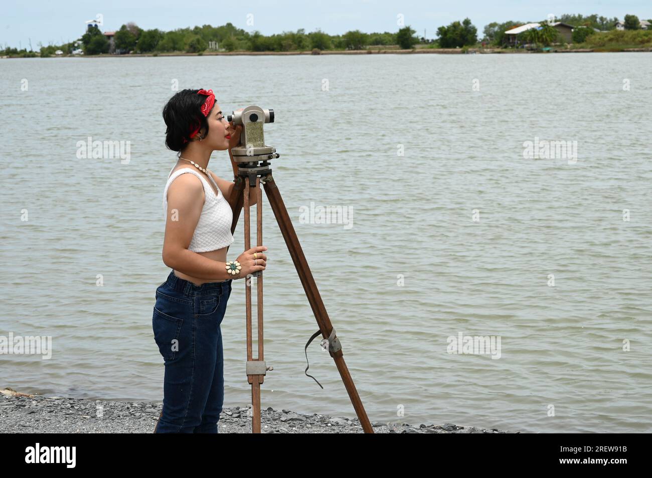 Hübsche asiatische Vermessungsfrau oder Ingenieurin, die mit Theodolith-Transitgeräten auf einer Baustelle im Freien arbeitet. Stockfoto