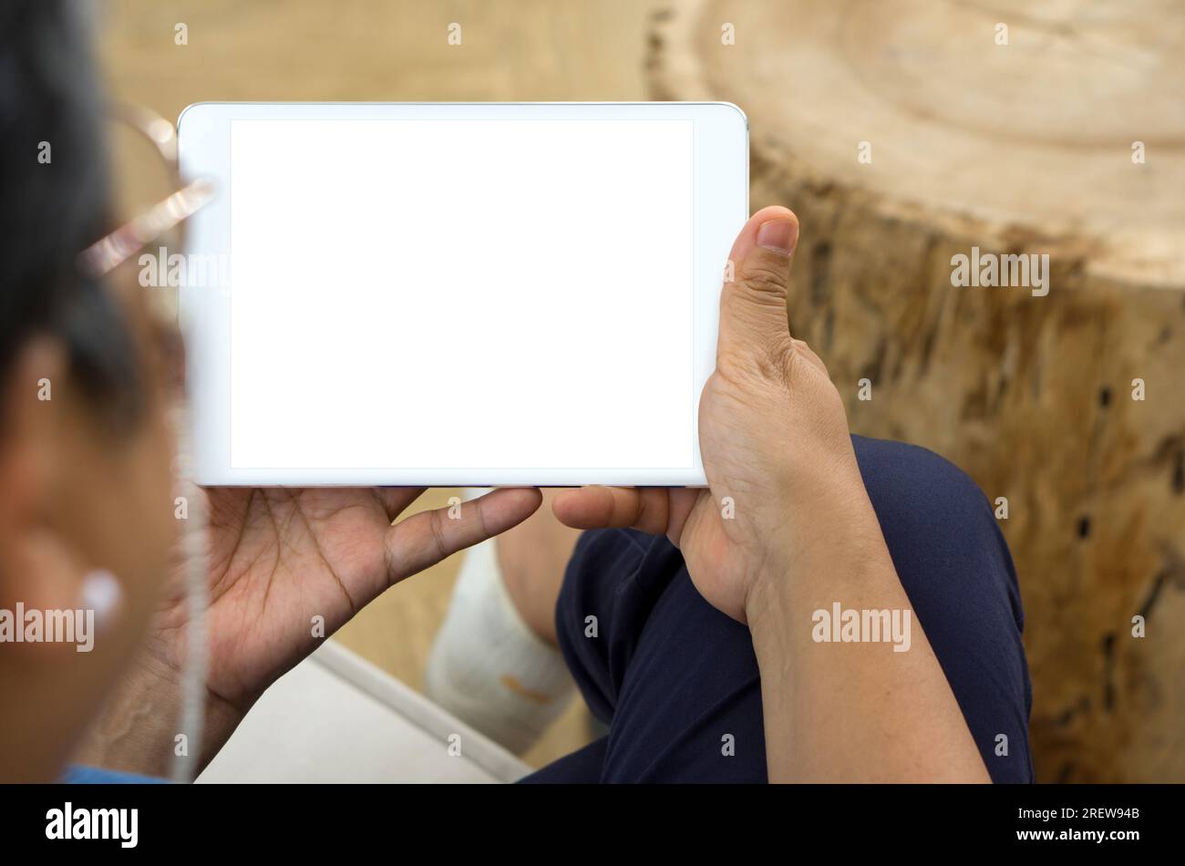 Eine erfahrene Frau, die professionell gekleidet ist und ein modernes Tablet mit einem sauberen, leeren Bildschirm in Richtung Kamera hält, mit einem ruhigen Gesichtsausdruck. Stockfoto