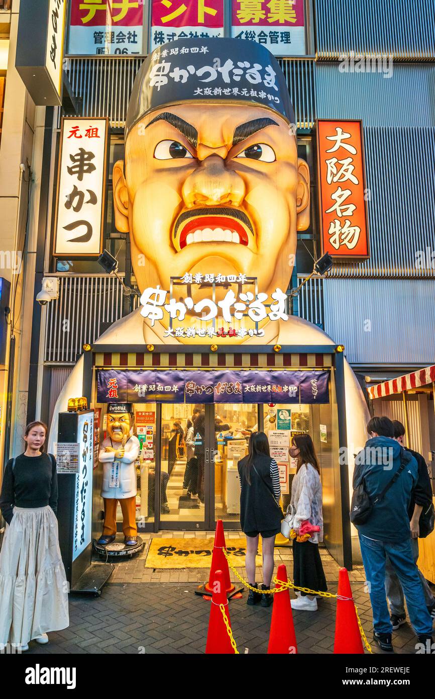 Die berühmte Fassade des Restaurants Kushikatsu daruma in Dotonbori, Osaka, bei Nacht. Eintritt mit der Gesichtsskulptur „wütender Koch“, die oben beleuchtet ist. Stockfoto