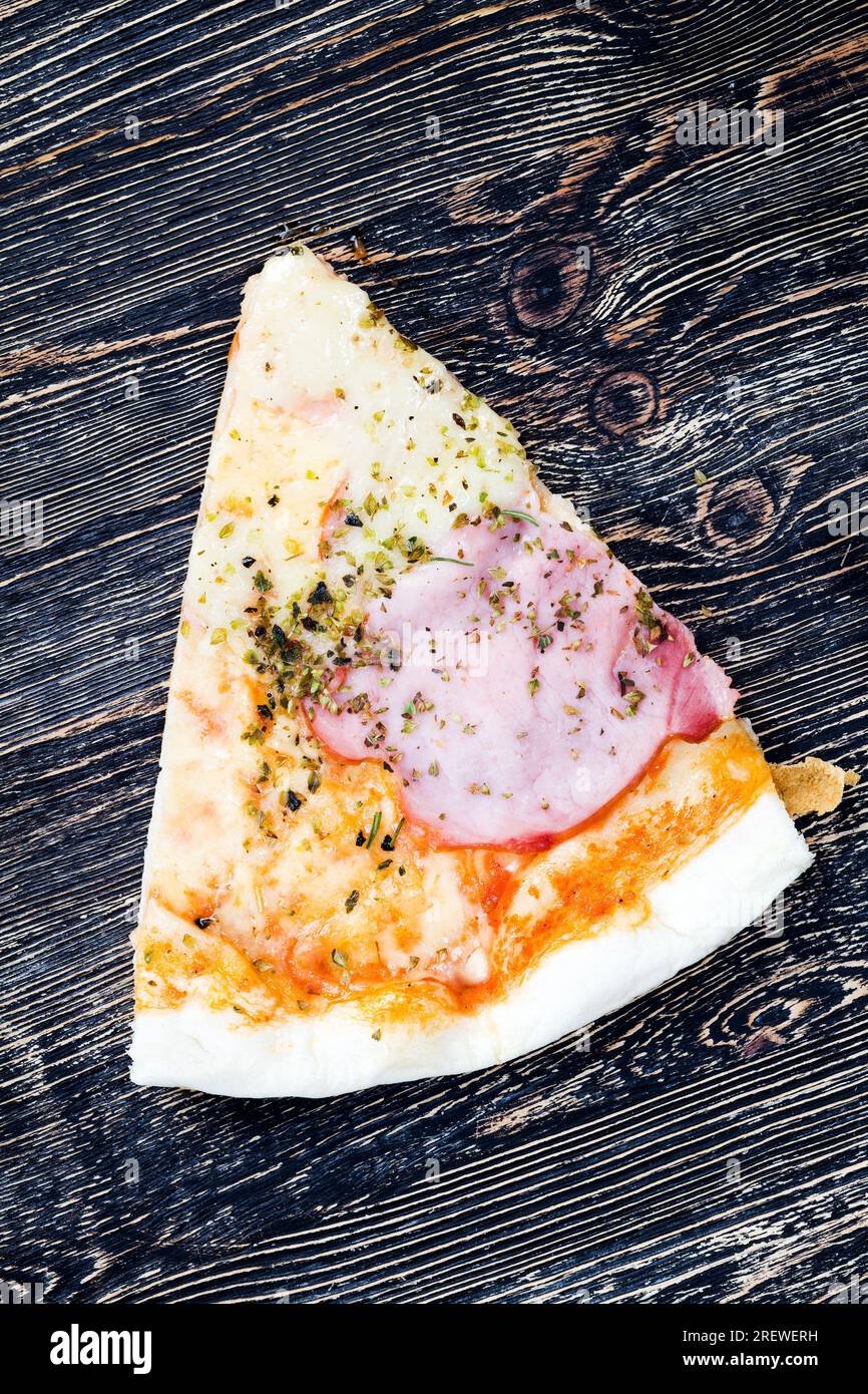 Eine Pizza gefüllt mit Schinken, Käse und anderen Zutaten, preiswertes Fast Food, ungesundes Essen Stockfoto