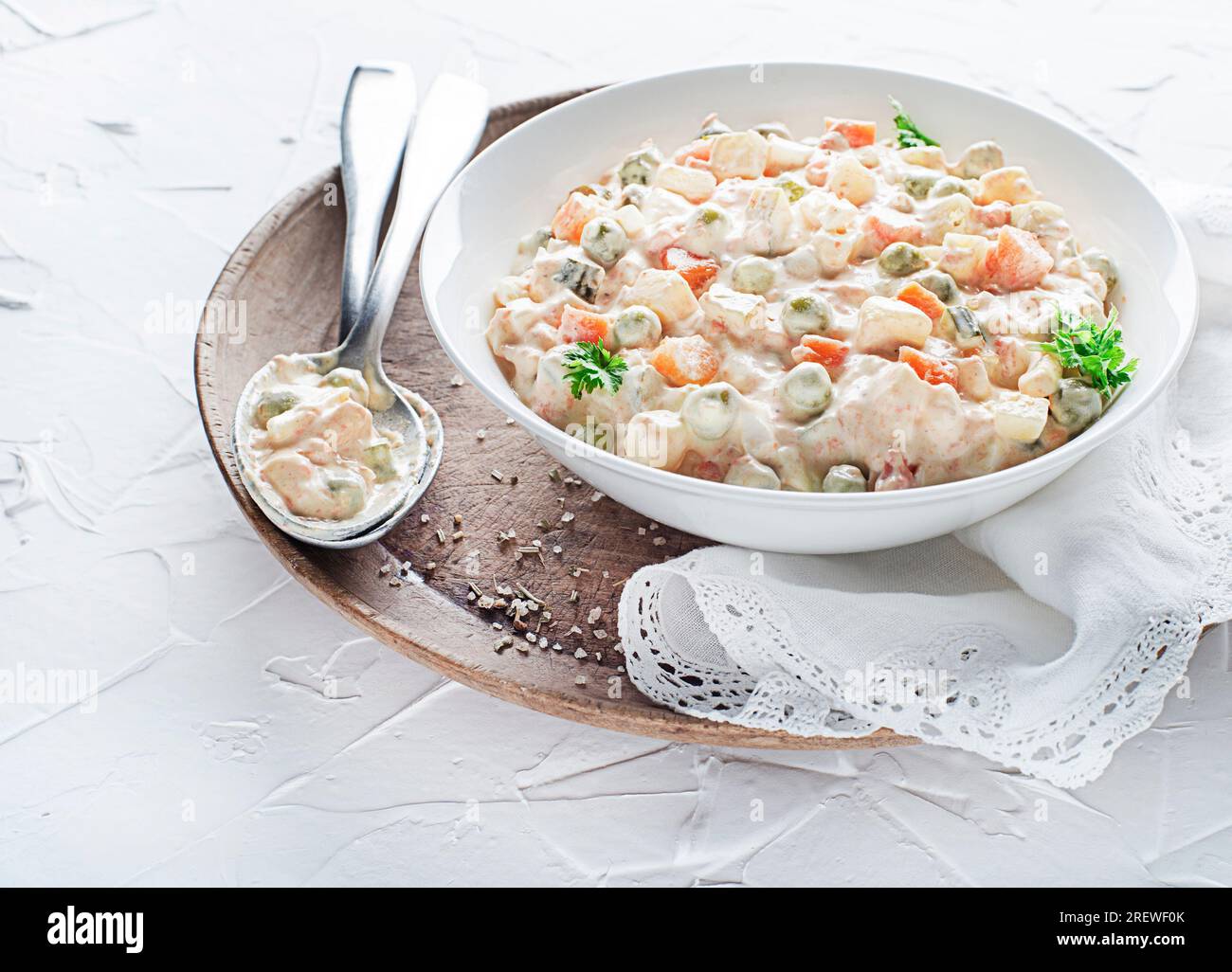 Schüssel mit russischem Salat oder olivier- oder französischem Salat mit Gemüse und Ei mit Mayonnaise auf dem weißen Tisch aus nächster Nähe Stockfoto