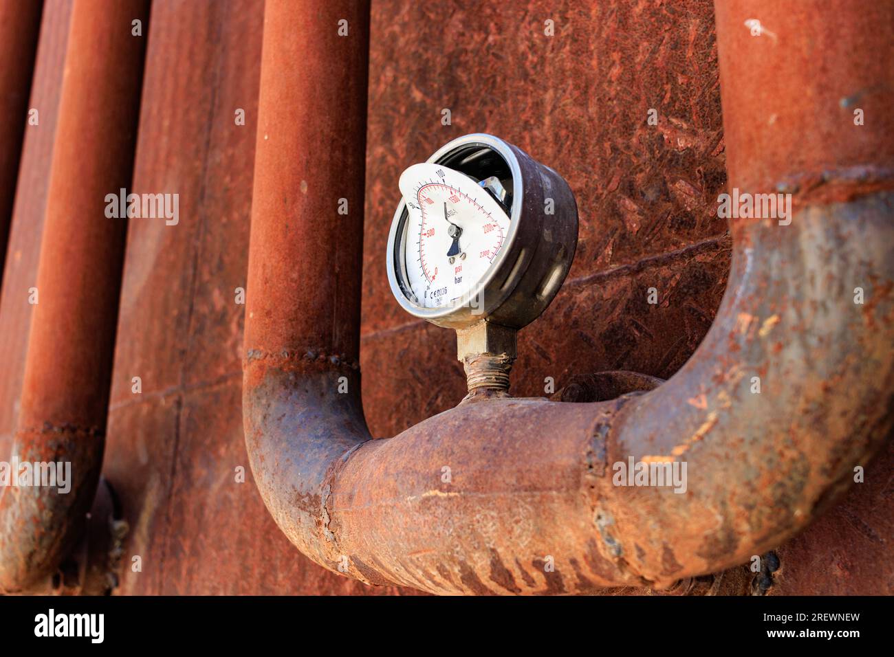 Ein kaputtes rostiges Manometer an einer rostigen Rohrleitung Stockfoto