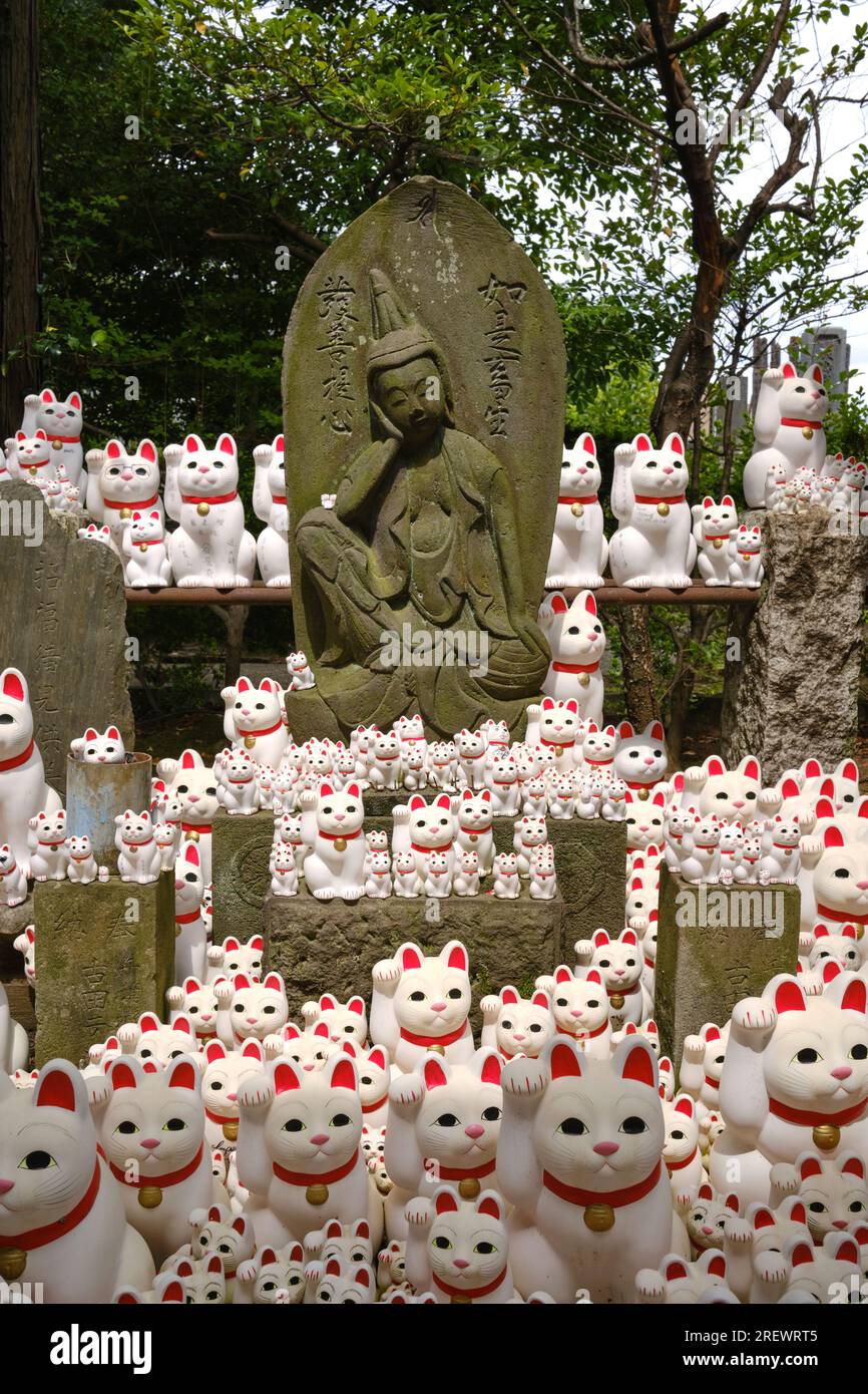 Am 2023. Juli winkende Katzen (Maneki Neko) um eine Buddha-Statue im Gotokuji-Tempel, Setagaya, Tokio Stockfoto