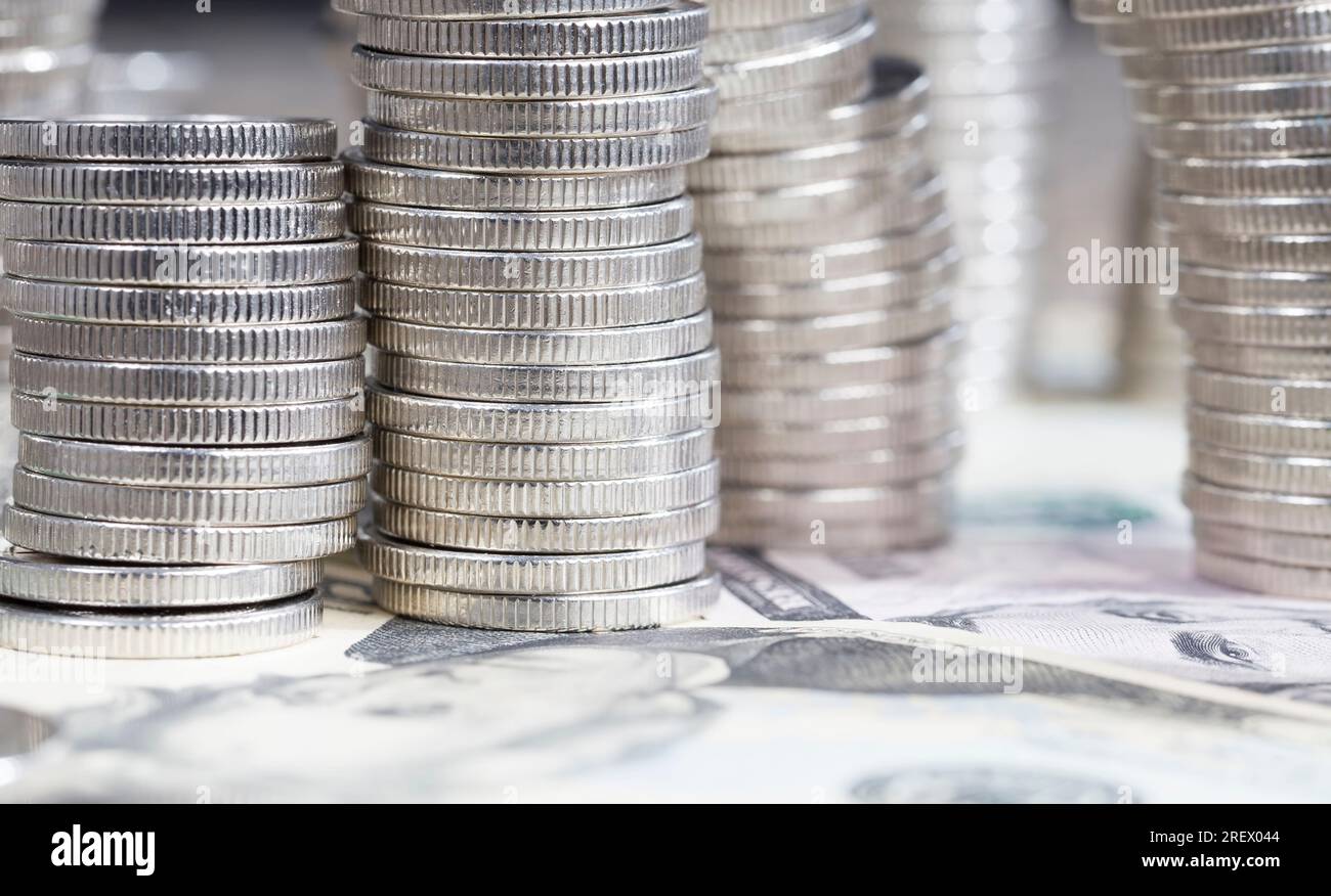 Eine große Anzahl silberner Metallmünzen, die auf amerikanischen Dollar gestapelt sind, gesetzliches Zahlungsmittel, das für Zahlungen im Staat verwendet wird, schöne Münze Stockfoto
