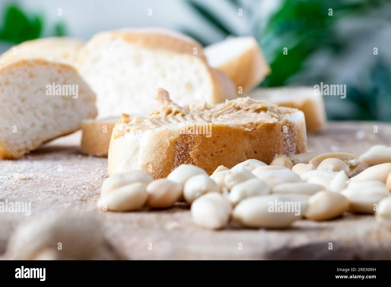 Zutaten für die Zubereitung eines schnellen Frühstücks mit Brot und Erdnüssen, Erdnusspaste geröstete Erdnüsse, köstliche Erdnussbutter und Weißbrot auf dem Tisch, Stockfoto